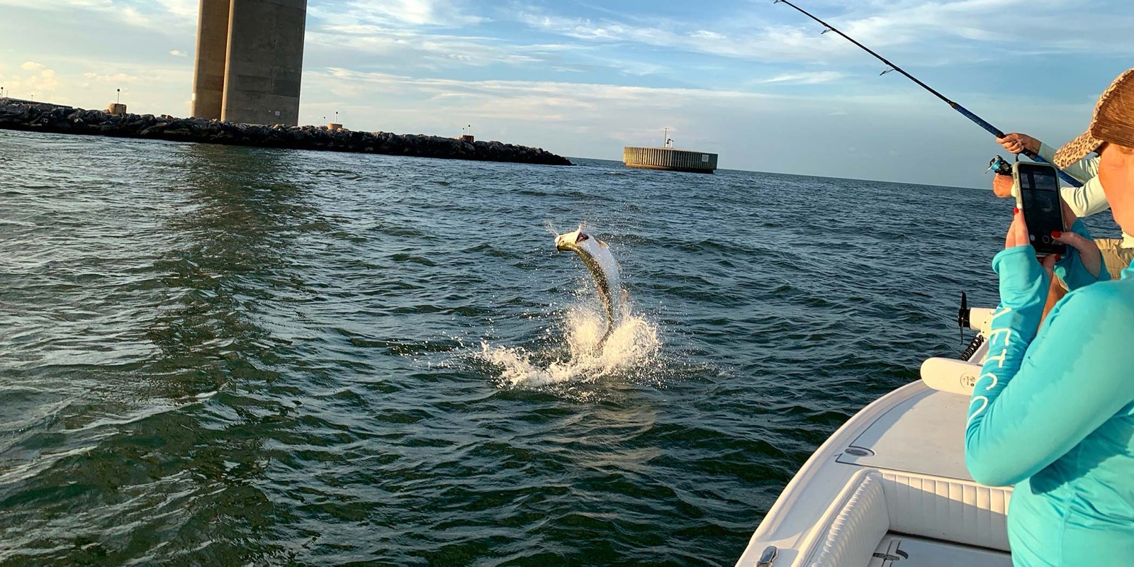 A tarpon jumping beside the boat near a Tampa Bay bridge
